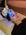 A woman lying down receiving a facial treatment with a blue light therapy device, handled by another person wearing gloves.